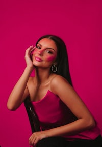 a beautiful woman in a pink dress posing on a chair